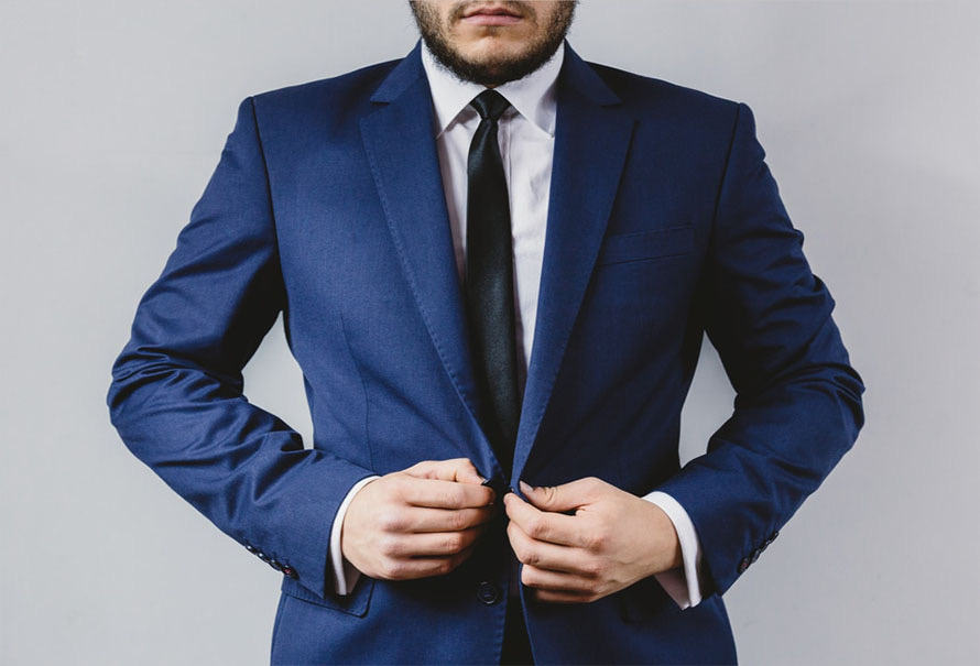 Professional in a navy suit, white shirt, and black tie buttoning his jacket
